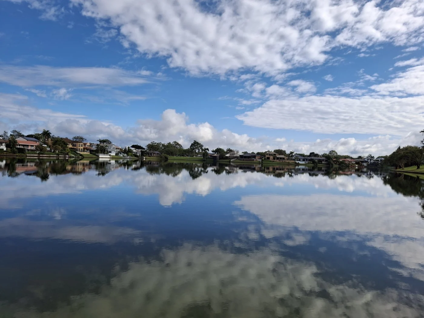Cloud reflections across a lake bordered by grass and trees