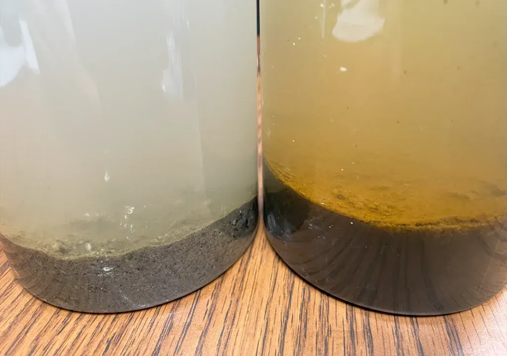 Two jars comparing coarse mineral material with fine dark organic sediment